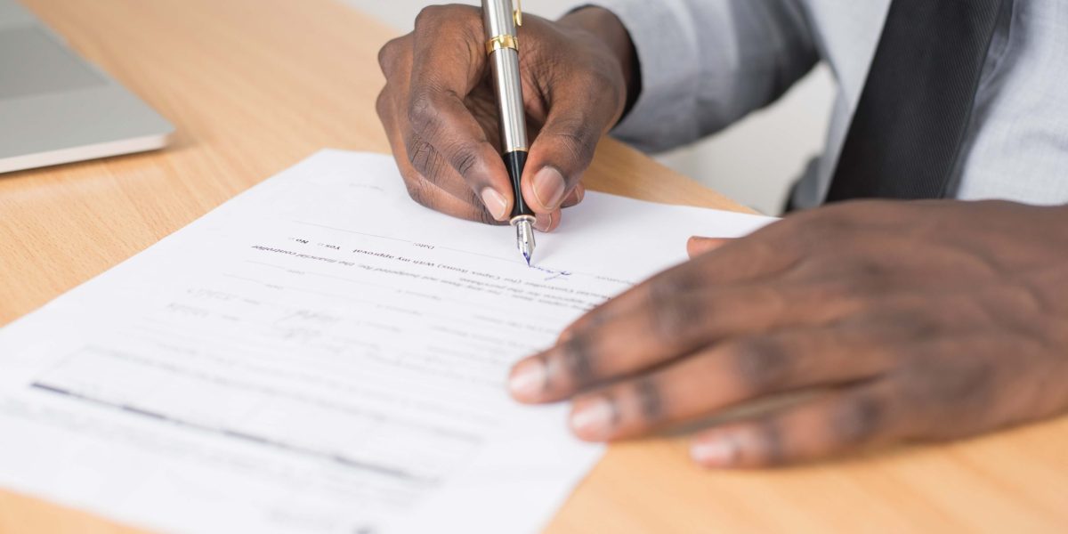 Personne écrivant sur du papier blanc avec un stylo